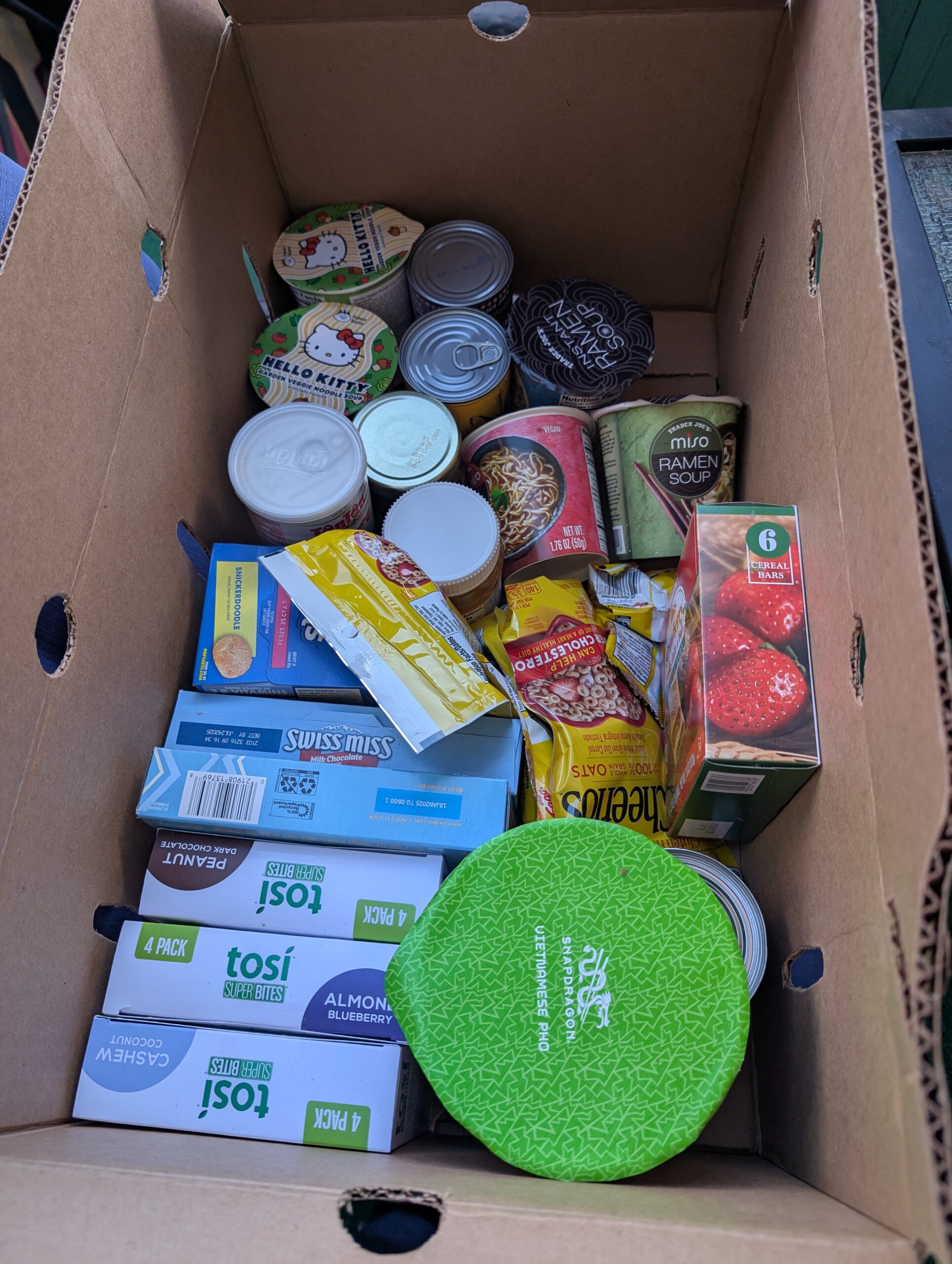 A photo of a cardboard box filled with breakfast bars, ramen, cereal, and other foods.