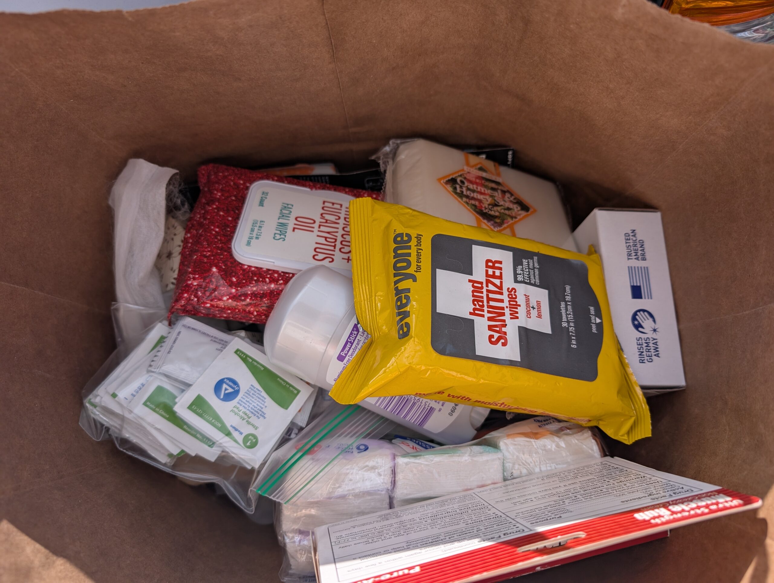 A photo of a cardboard box filled with hand sanitizer, deodorant, soap, and other personal health items.