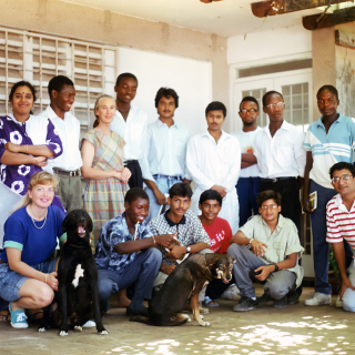 A large group of young adults pose for a photo on a porch.