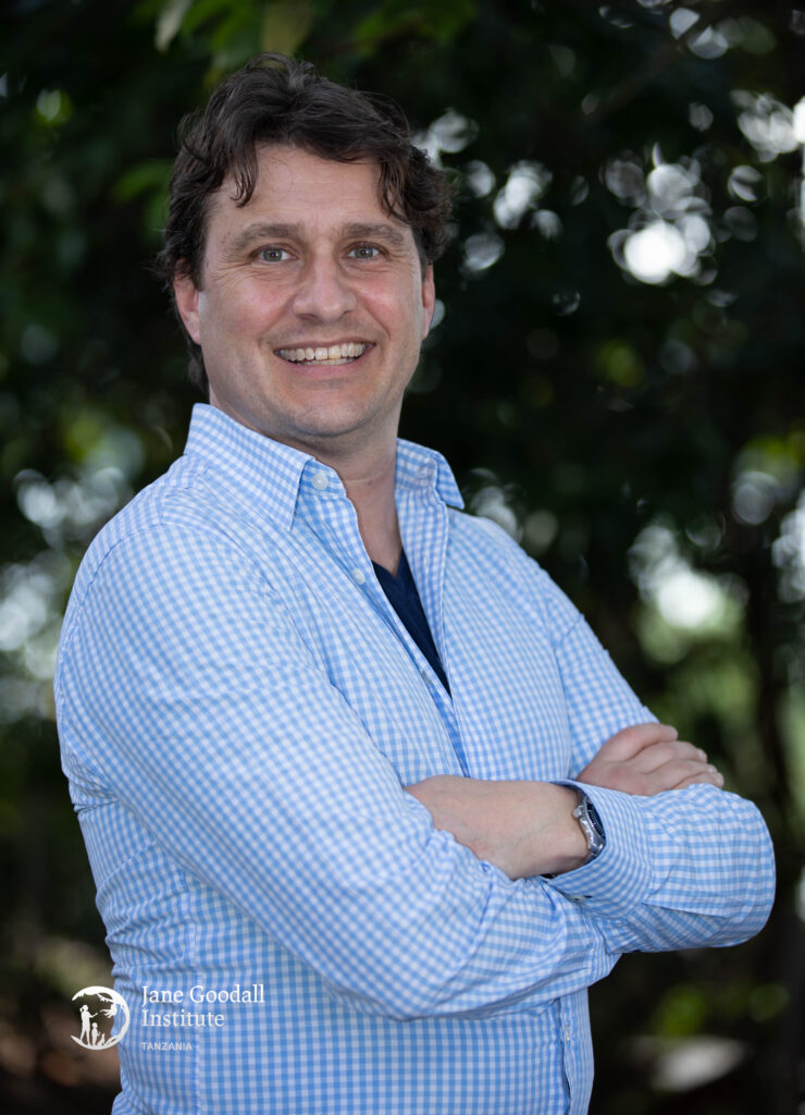Dr. Marc Fourrier smiling wearing a light blue collared shirt in a forest setting.